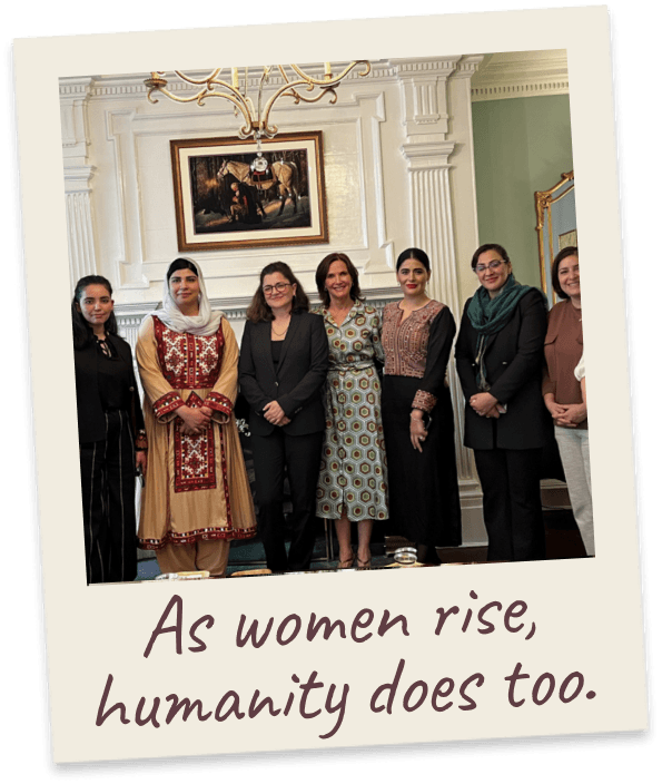 As women rise, humanity does too. A group of women in mixed traditional and Western dress in a gilded, chandeliered reception room.