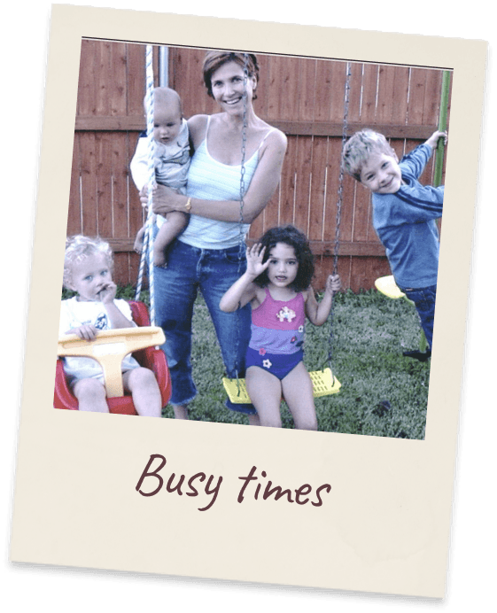 Busy times. Margie on a lawn holding a baby on her hip with three more young children around her.