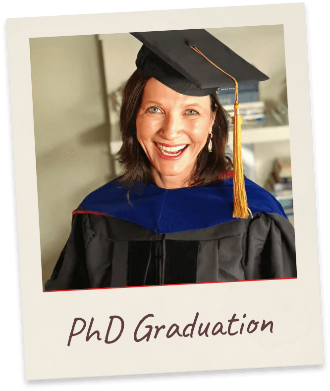 PhD Graduation. Margie in black academic regalia with a navy doctoral hood and gold-tasselled mortarboard, laughing.