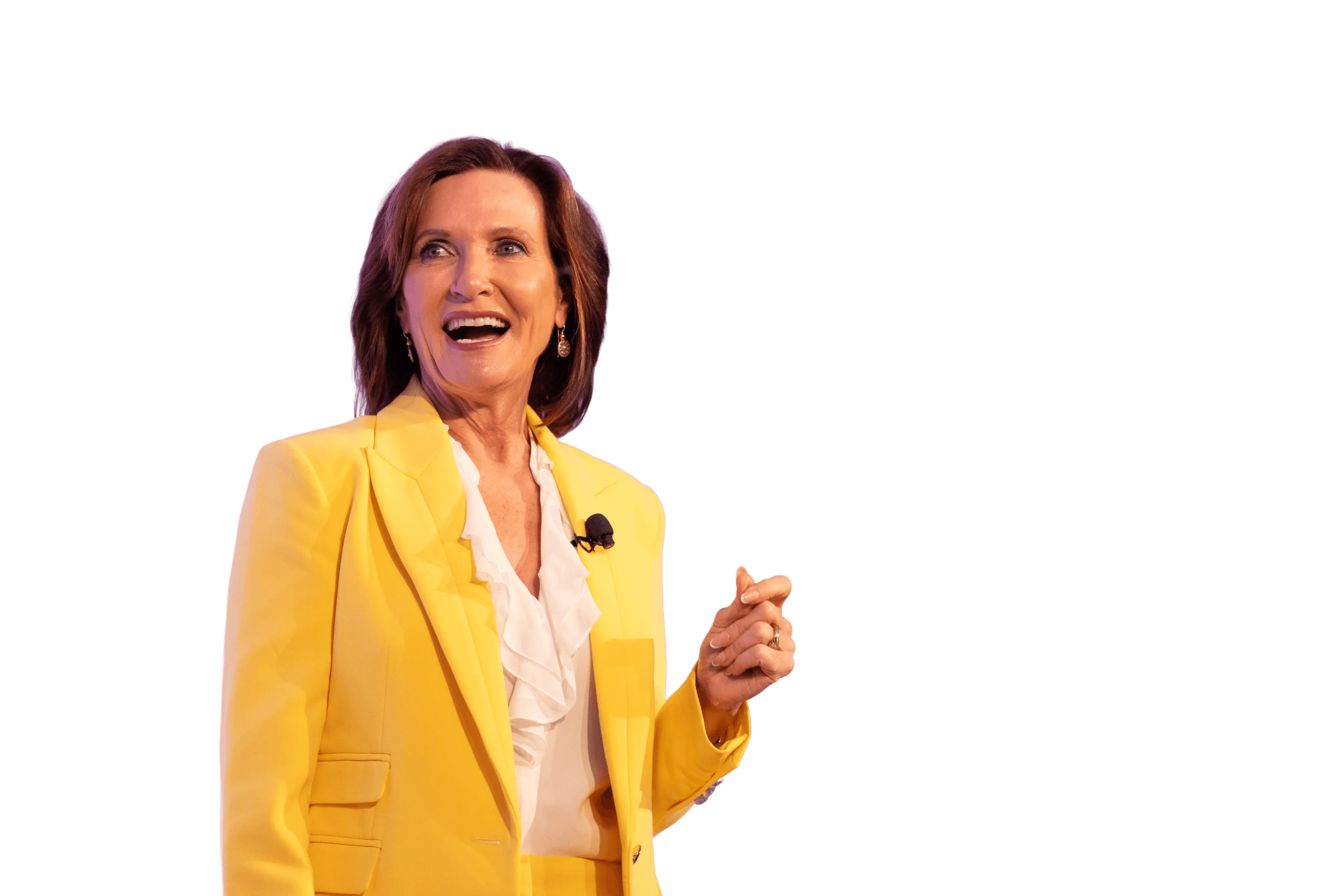 Dr. Margie Warrell speaking on stage in a bright yellow suit, one hand raised mid-gesture, against a violet stage wash